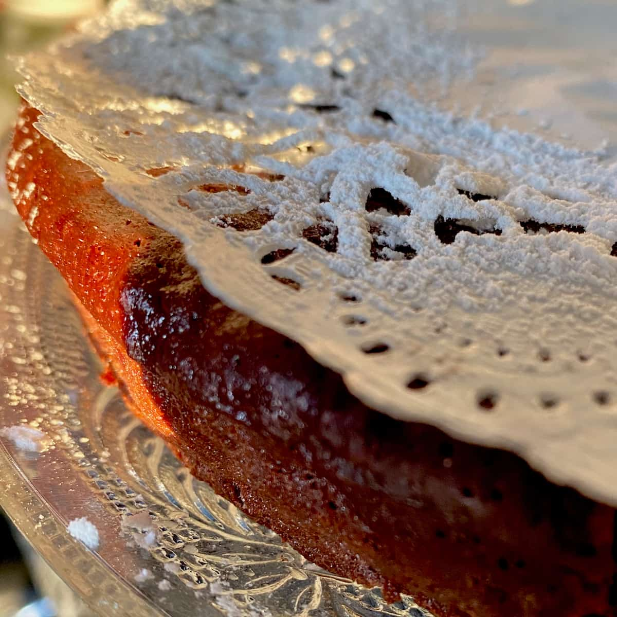 dusting a chocolate cake with icing sugar over a paper doilly