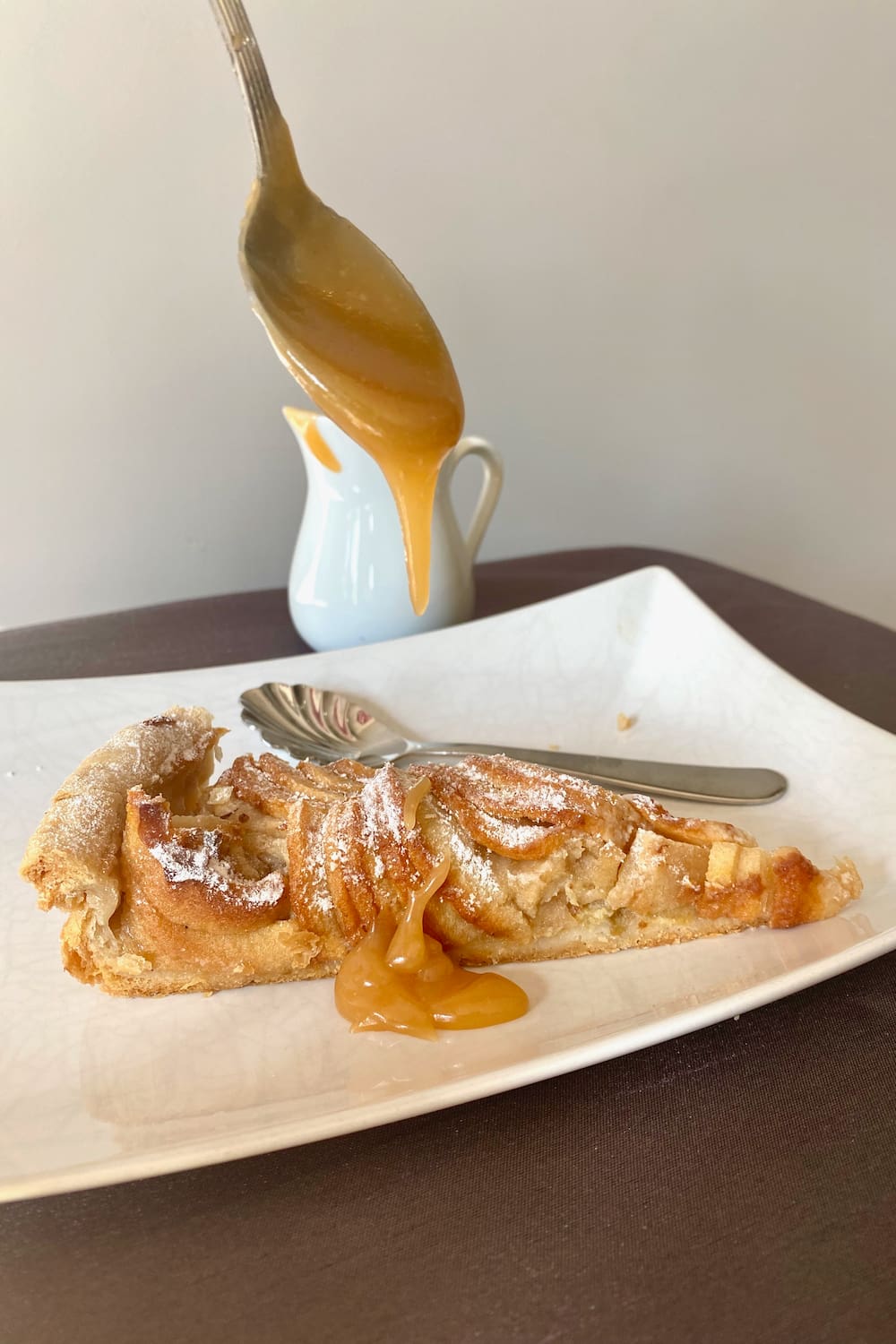 Spooning caramel sauce on apple tart