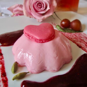 individual rose panna cotta with a dark cherry and cardamom sauce