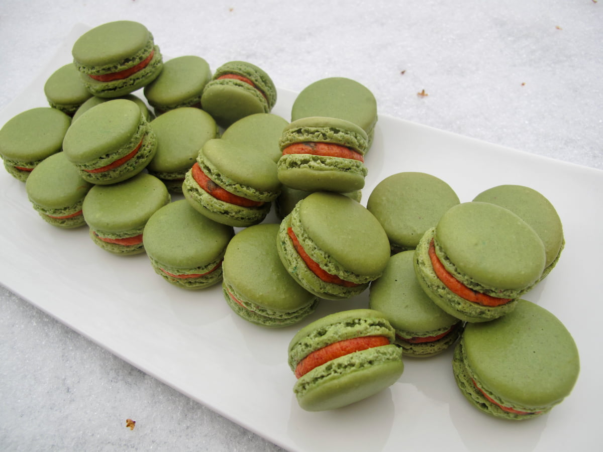 mini green and red macarons on white plate in the snow