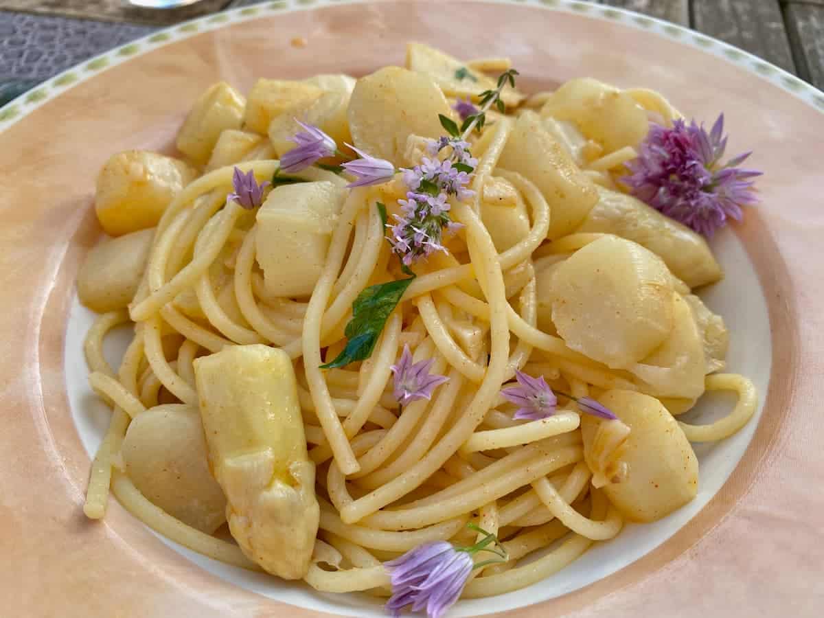 creamy lemon spaghetti with white asparagus and topped with chive flowers