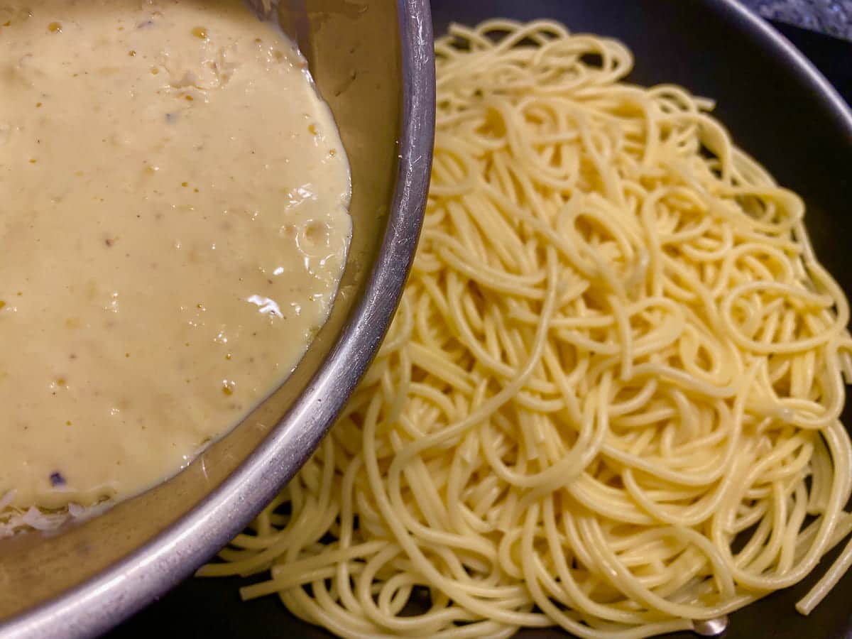 adding lemon cream sauce to cooked spaghetti