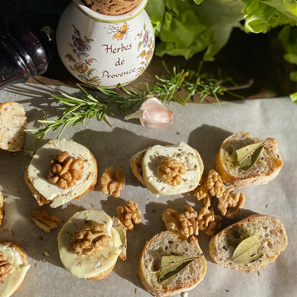 slices of baguette topped with bay leaf, goat cheese, walnut and rosemary