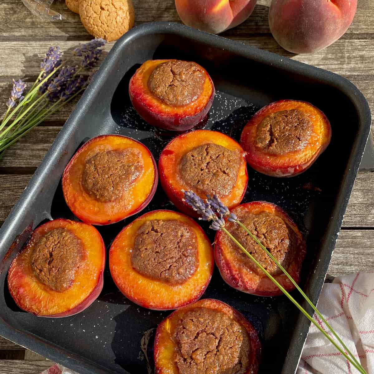 baking tin with baked peach halves stuffed with amaretti filling and lavender