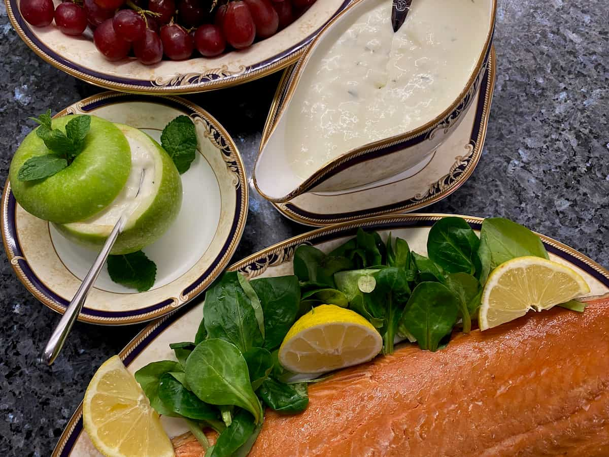 green apple filled with a horseradish sauce next to a sauce boat served with smoked salmon