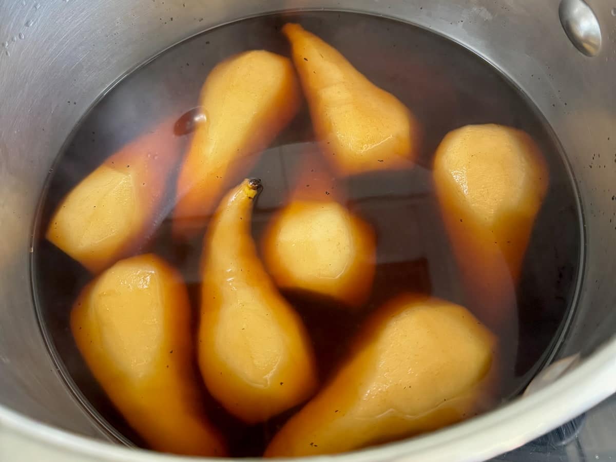 halved pears poaching in a coffee syrup