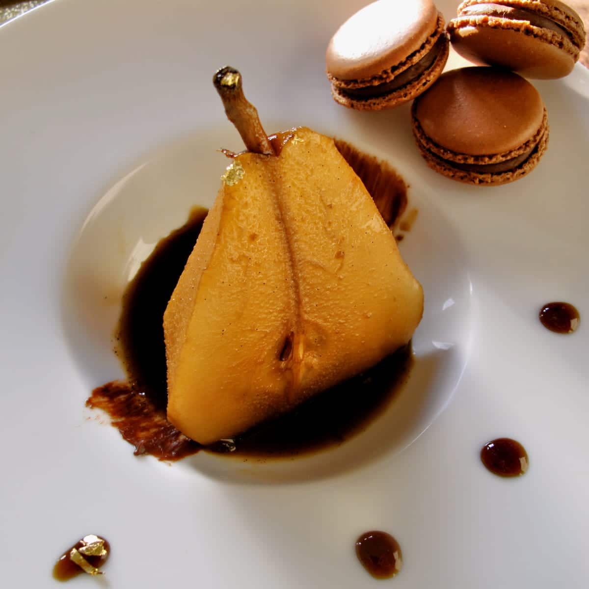 half a poached pear sitting in a puddle of coffee sauce
