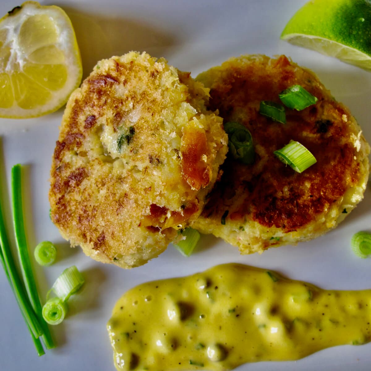 fishcakes with tartare sauce, topped with chives and lemon wedges