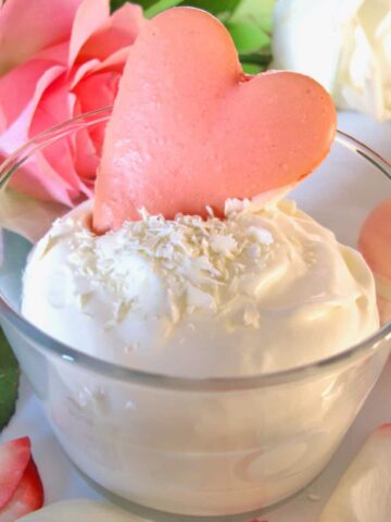 white chocolate mousse in a bowl with rose petals and love heart macaron