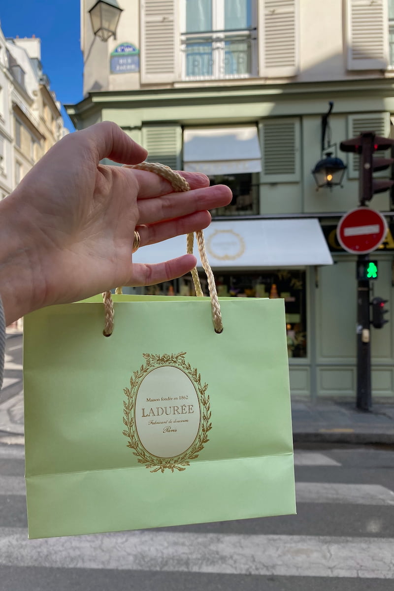 holding up a famous green pastry bag in Paris