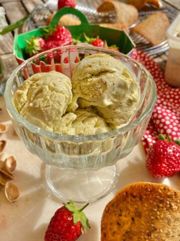 bowl of pistachio ice cream with flecks of vanilla and surrounded by pistachio shells