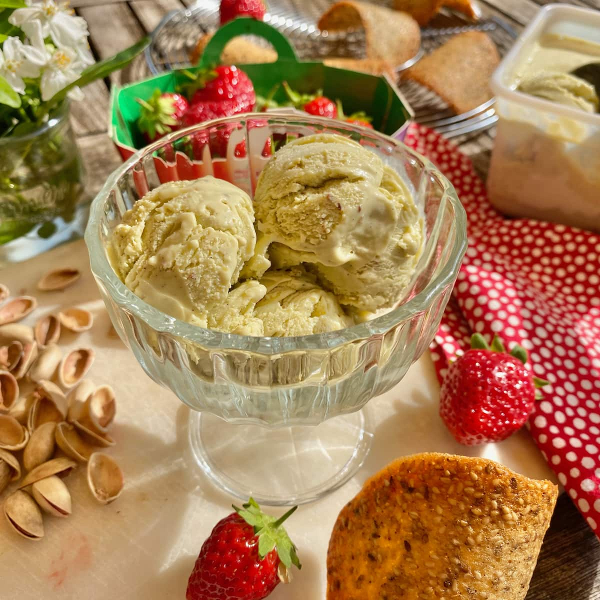 bowl of pistachio ice cream with flecks of vanilla and surrounded by pistachio shells