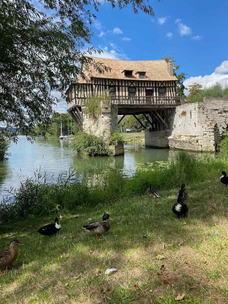 old French timbered mill on stilts over the river with ducks below