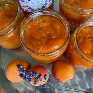 glass jars filled with bright orange apricot jam with sprigs of purple lavender