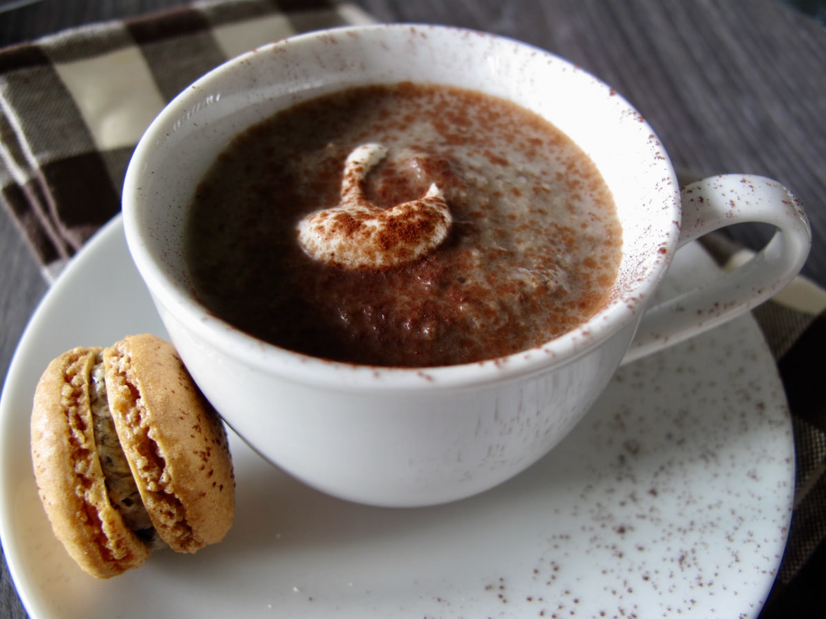 coffee cup of creamy mushroom soup served with a mini truffle macaron