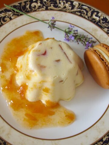 individual ice cream with candied fruits on plate with lavender, apricot sauce and a macaron