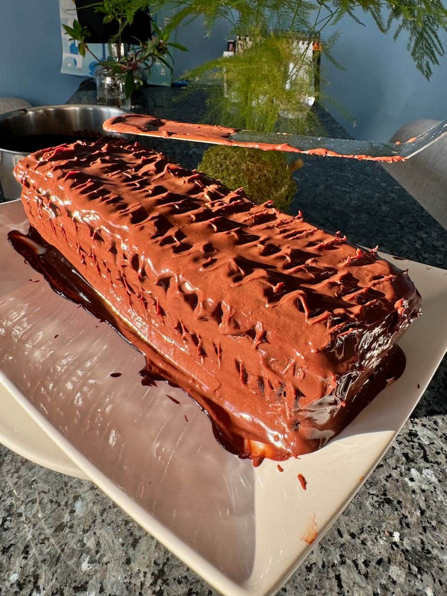 spreading on chocolate ganache on a rectangular cake, making patterns with the knife