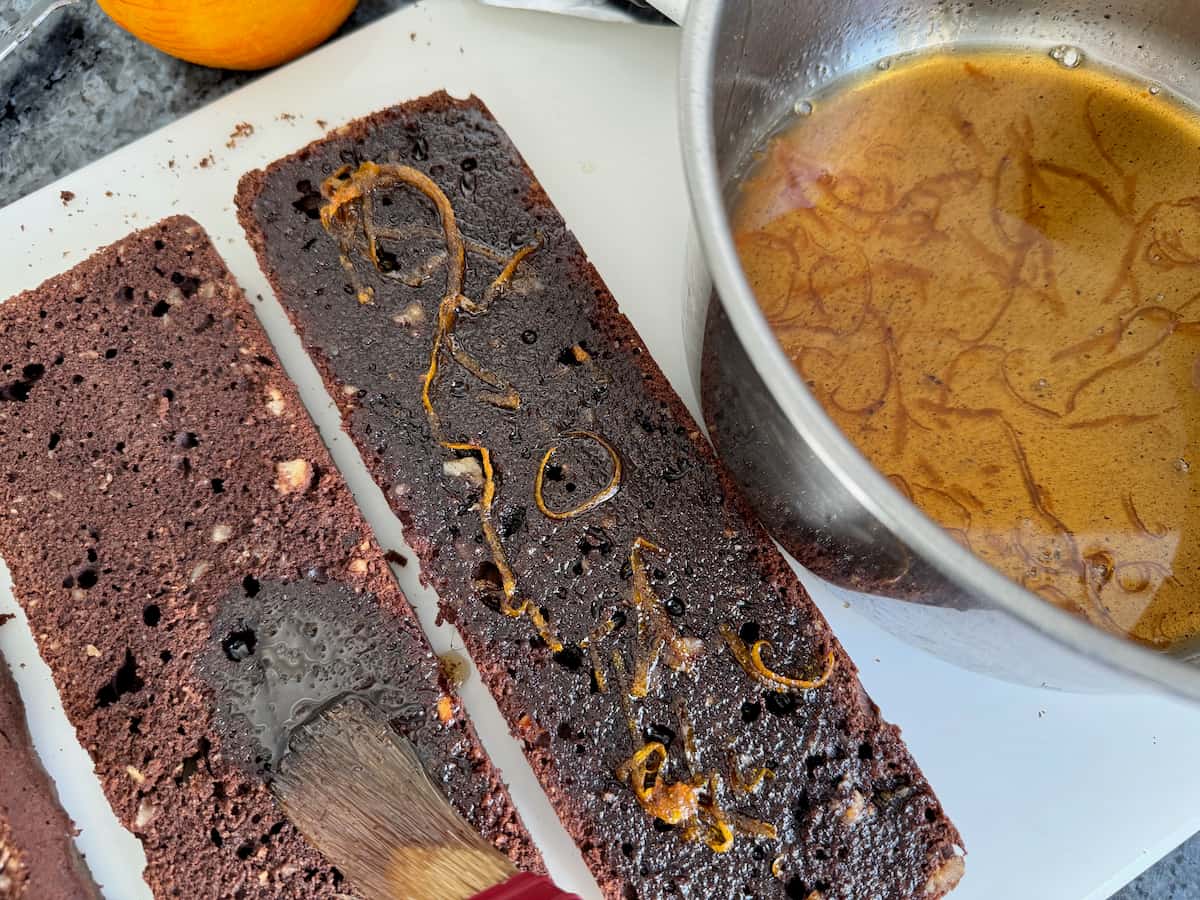 Step-by-step recipe of Patrick Roger's chocolate cake - MadAboutMacarons.com brushing on an orange rum syrup over 3 cake layers