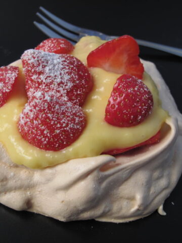 mini pavlova meringue nests filled with lemon cream topped with strawberries
