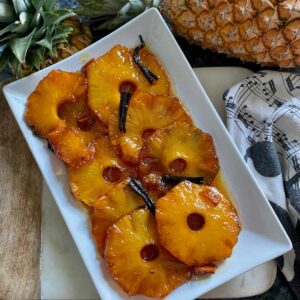 golden, shiny roasted caramelised pineapple slices on a plate with vanilla