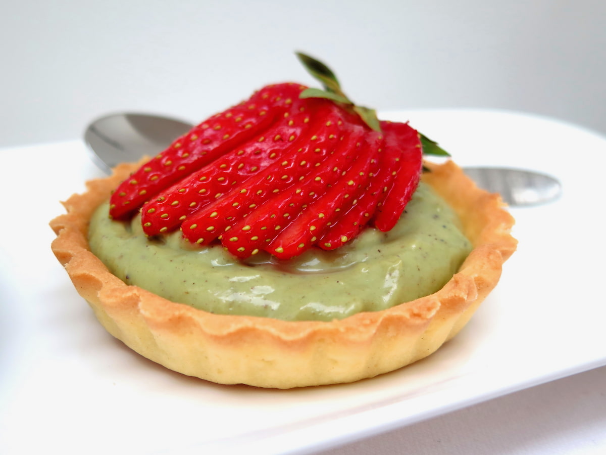 tartlet with green pistachio cream filling topped with a fanned out strawberry