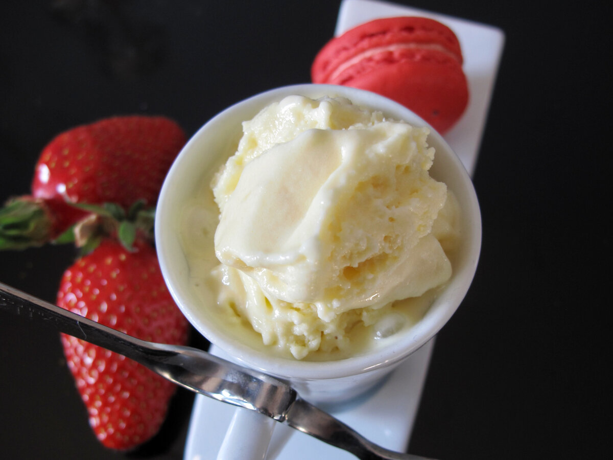 scoop of creamy lemon ice cream with strawberries and a macaron