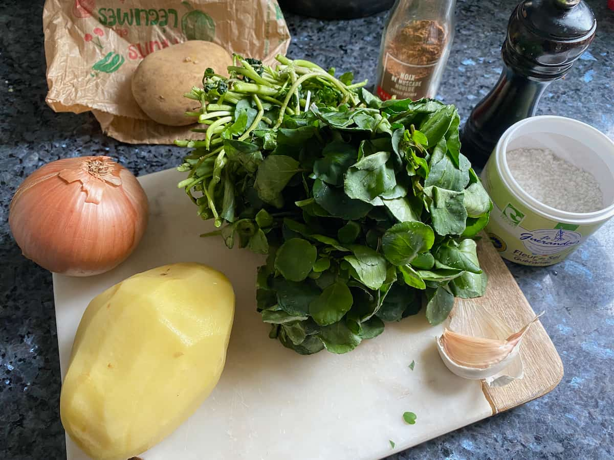 bunch of watercress, a peeled potato, salt, nutmeg, pepper, garlic and onion