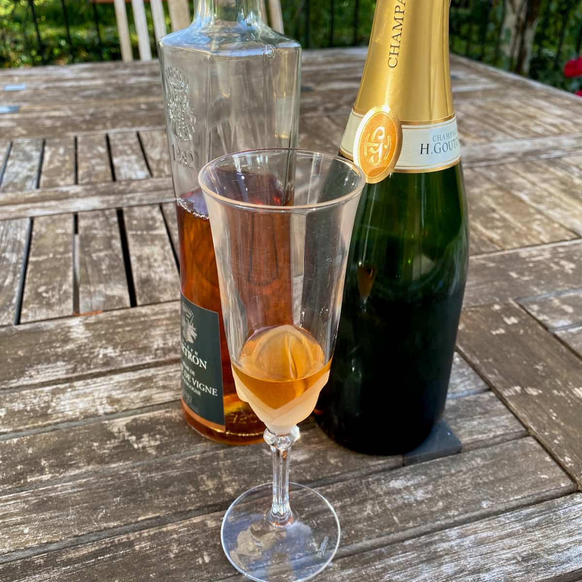 glass with peach liqueur next to Champagne