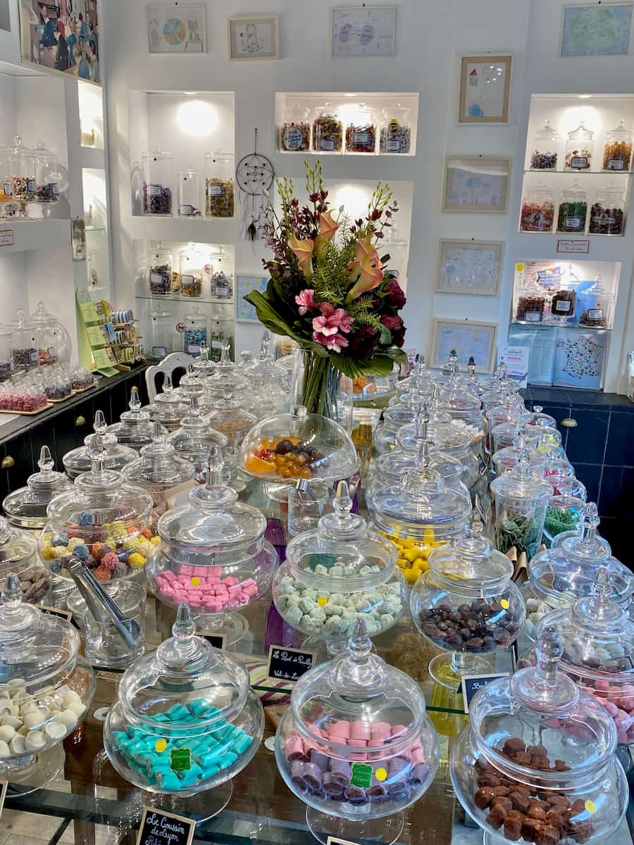 table hidden by rows of glass apothecary jars containing colourful sweets or candies