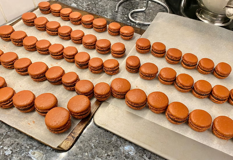 line-up of shiny chocolate macarons sandwiched together at home