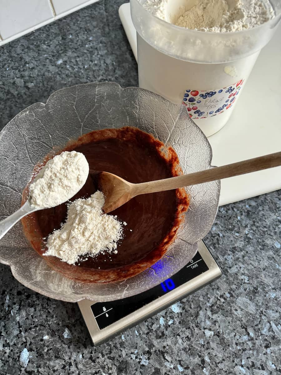 adding a little flour to a melted chocolate and egg mixture