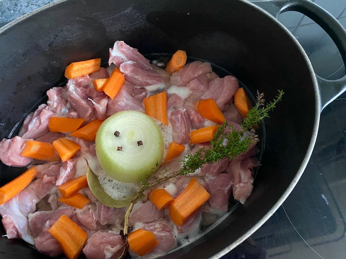 meat, carrots and onion studded with cloves in a big black pot