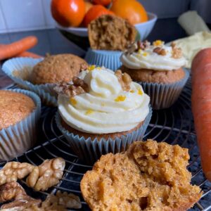 moist fluffy muffins with two topped with a spiral of cream cheese frosting with orange zest