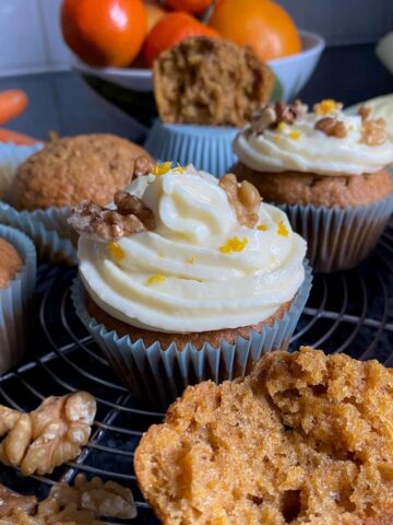 moist fluffy muffins with two topped with a spiral of cream cheese frosting with orange zest