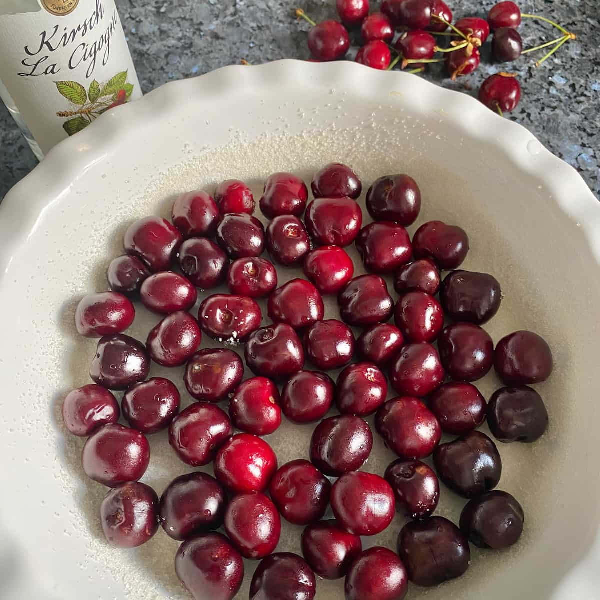 dark cherries in a buttered and sugared ovenproof dish ready to pour in clafoutis batter