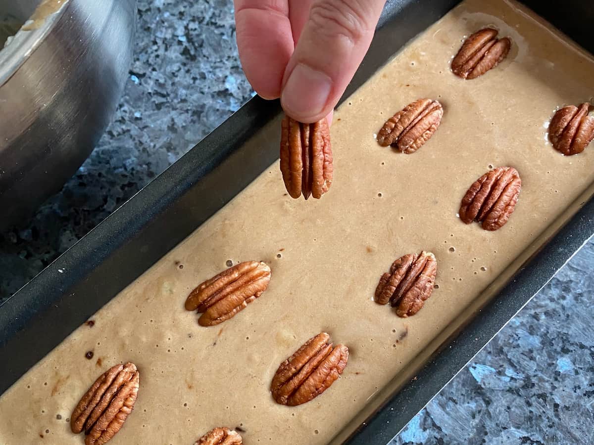 adding pecan nuts to the surface of banana cake before going in the oven