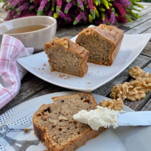 spreading cream cheese on a slice of banana cake