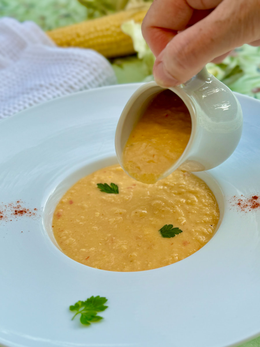 soup plate with a porcelain just pouring corn chowder