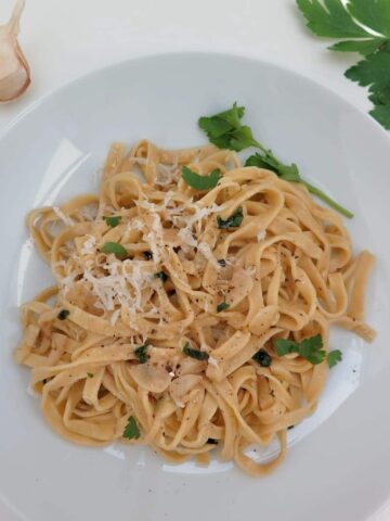bowl of fresh pasta noodles with parsley and grated cheese