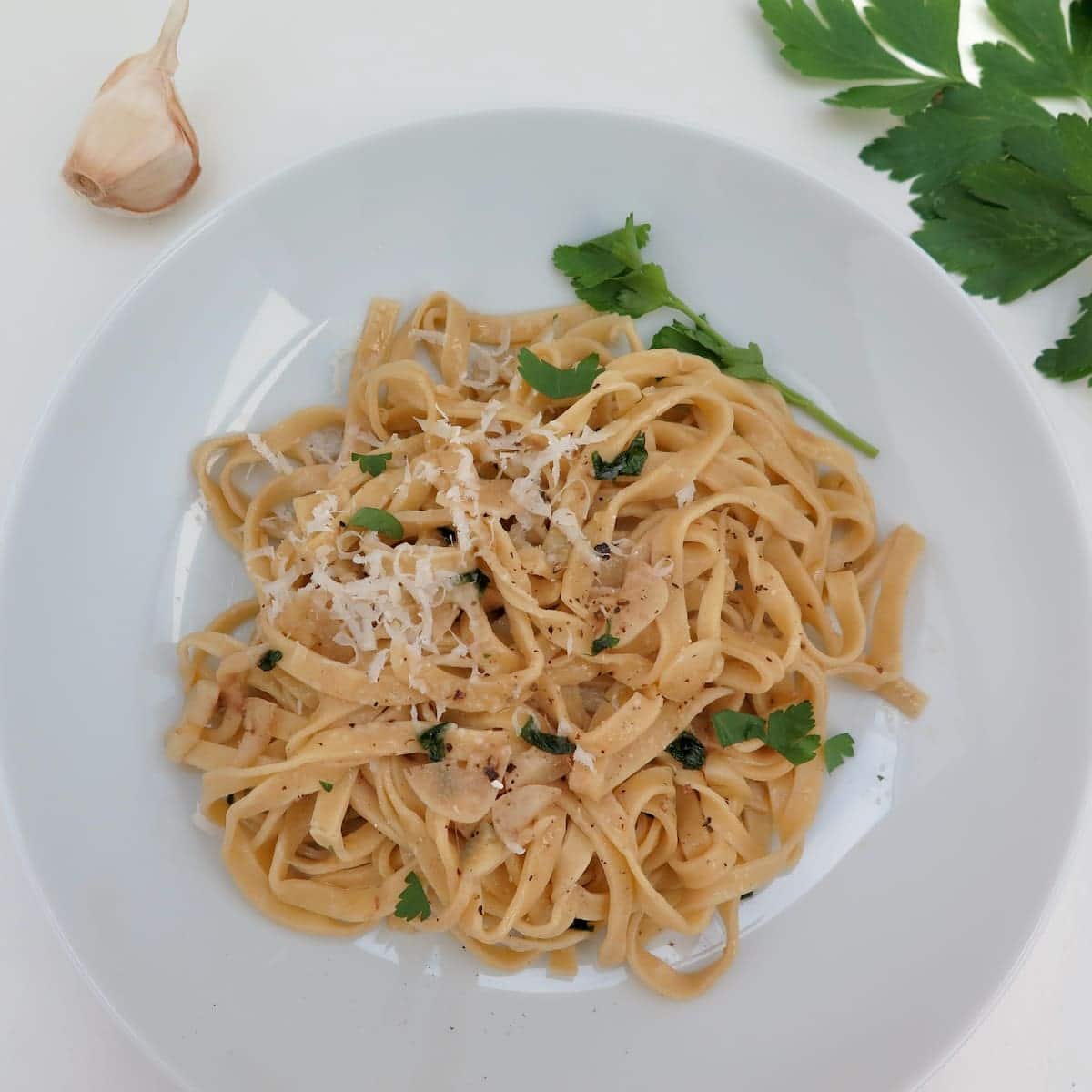 bowl of fresh pasta noodles with parsley and grated cheese