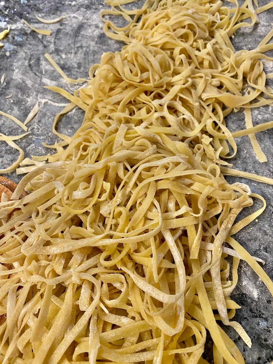 ribbons of homemade noodles drying on the counter with flour