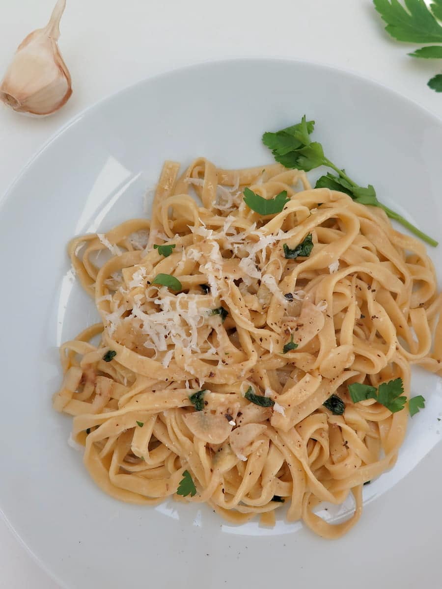 bowl of flat egg noodles served with grated cheese and parsley