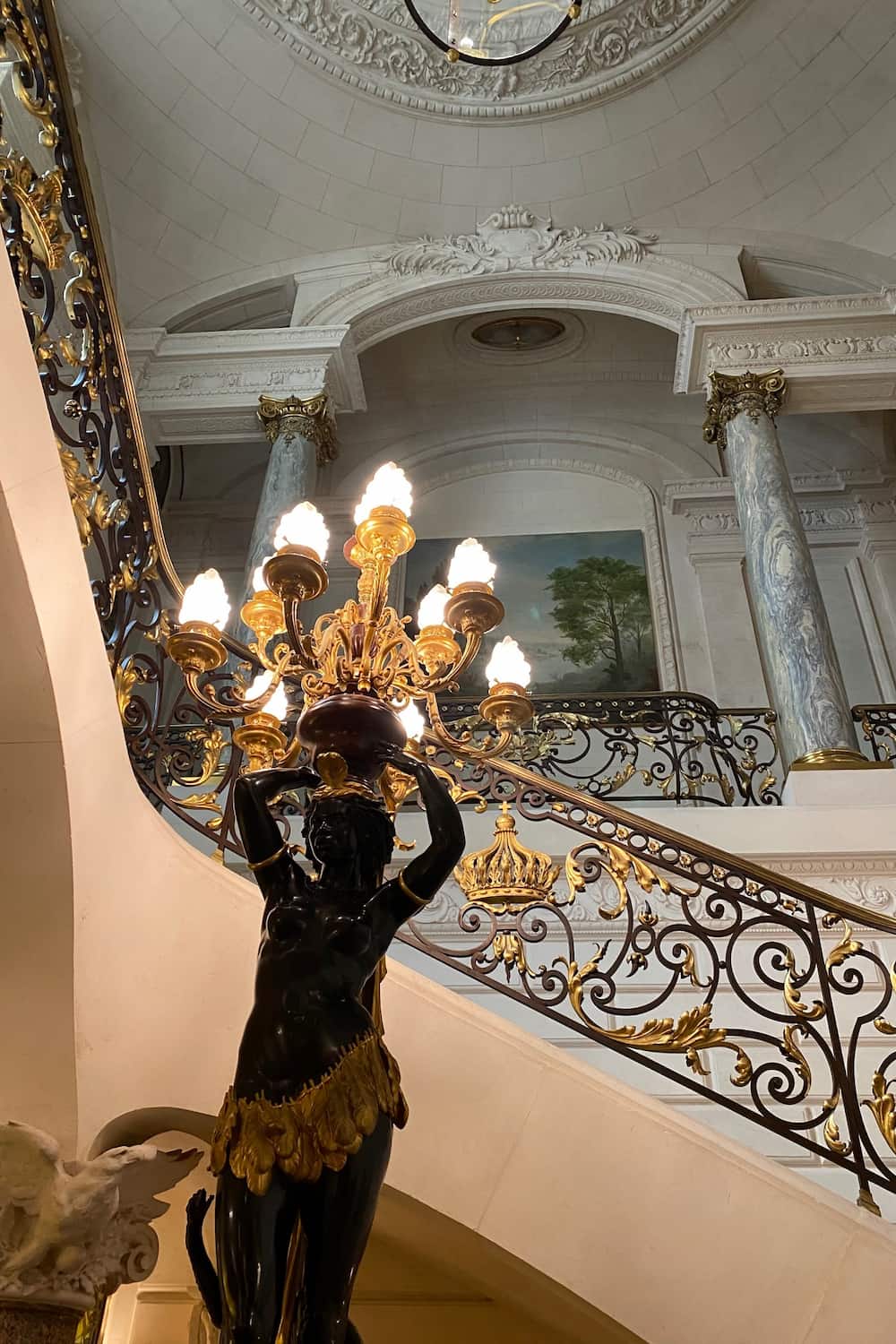ornate staircase with lights and statue