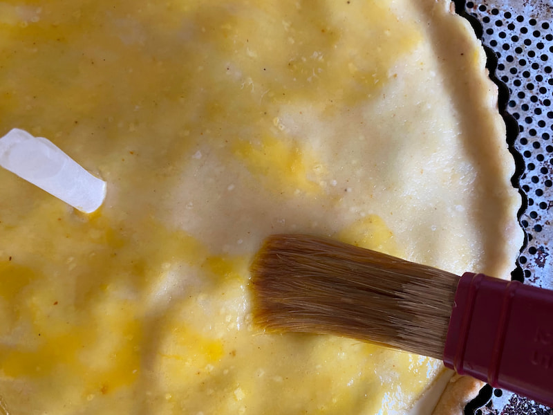 brushing egg yolk glaze on a pie