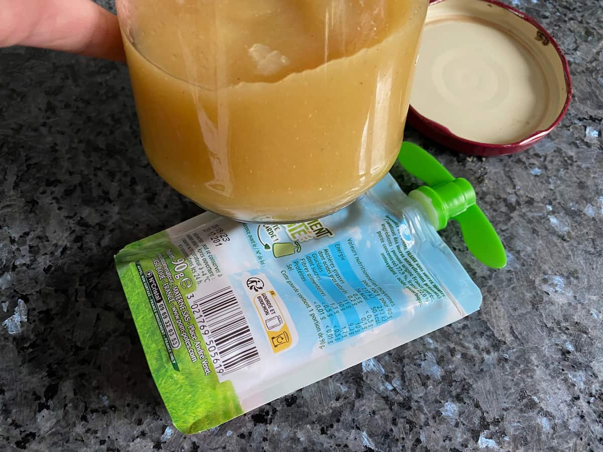 jar of liquid homemade apple sauce next to a plastic container of a commercial version