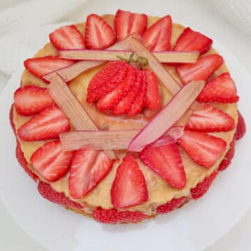rhubarb and custard cheesecake, decorated with rhubarb chips and strawberries