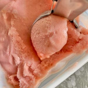 ice cream scoop of pink sorbet in a tub