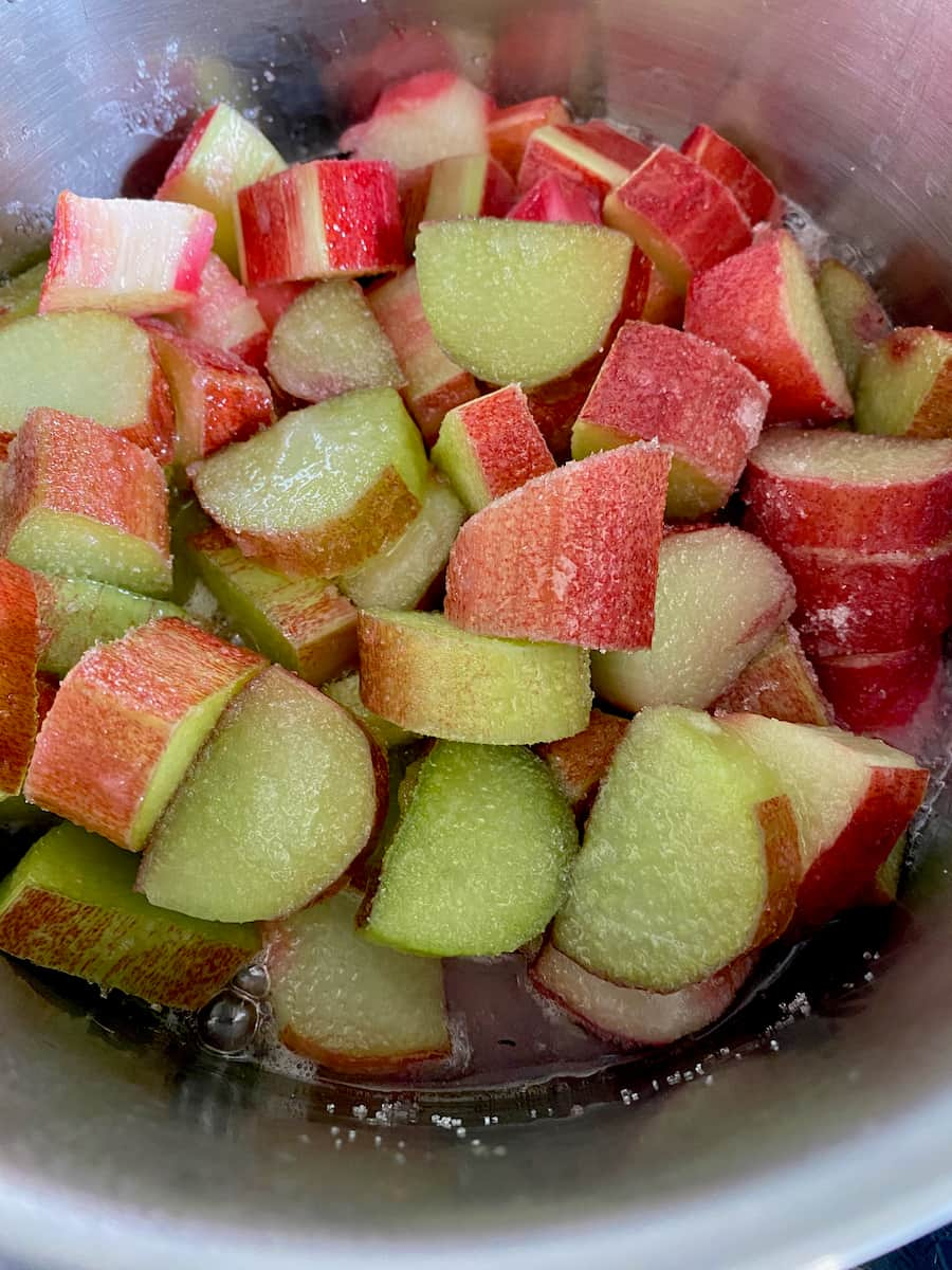 sliced rhubarb unpeeled in a pan of water and sugar