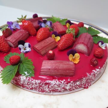 pink glazed cake topped with roasted rhubarb, strawberries and flowers