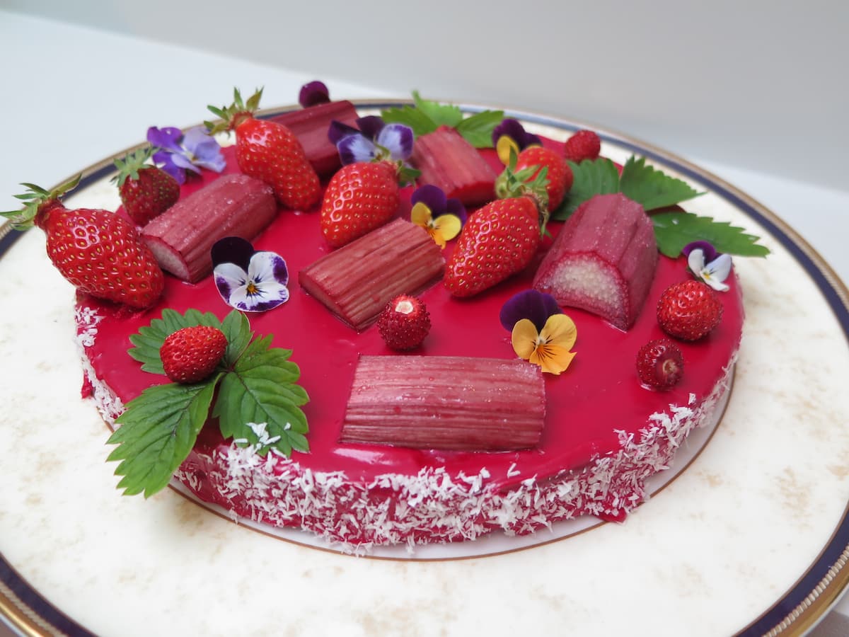 pink glazed cake topped with roasted rhubarb, strawberries and flowers